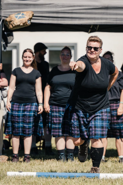 Eine Sportlerin im Kilt wirft einen großen Stein im Wettbewerb der Games